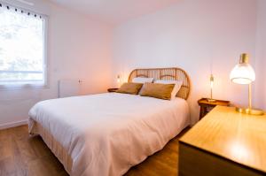 a white bedroom with a large bed and a window at Cosy, lumineux, proche du centre-ville in Caen