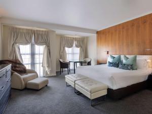 a hotel room with a large bed and a table at Sofitel Queenstown Hotel & Spa in Queenstown