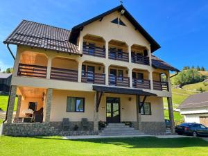 a large house with a gambrel roof at Matei Moieciu De Sus in Moieciu de Sus