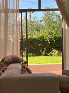 - un canapé dans le salon doté d'une grande fenêtre dans l'établissement Villa Magnolia - Amelkis Golf, à Marrakech