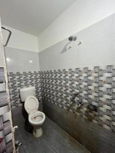 a bathroom with a toilet and a tiled wall at Goroomgo Beach Heaven Near Sea Beach Puri in Puri