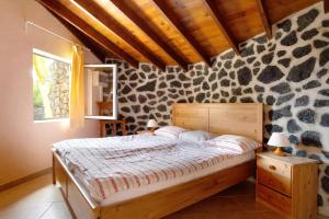 a bedroom with a bed and a stone wall at Casa Verde in Teguise