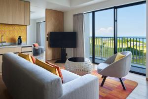 a living room with a couch and a television at Hilton Club The Beach Resort Sesoko in Motobu