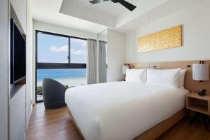 a bedroom with a large white bed and a view of the ocean at Hilton Club The Beach Resort Sesoko in Motobu +34 photos