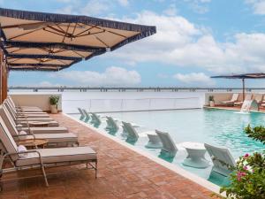 une piscine avec des chaises longues et une piscine dans l'établissement Sofitel Legend Casco Viejo, Panama City, à Panama City