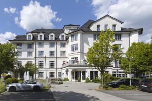 Un bâtiment blanc avec une voiture garée devant. dans l'établissement Sunderland Hotel, à Sundern