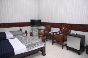 sypialnia z 2 łóżkami, telewizorem i krzesłami w obiekcie Hotel Serina Inn w Kalar Goth