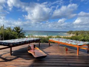 2 bancos en una terraza de madera con la playa en umbila:Barra, en Inhambane