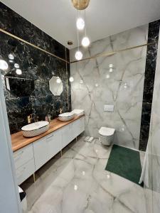 baño con 2 lavabos y pared de mármol en Premium Exclusive Suite, en Nowy Dwór Mazowiecki