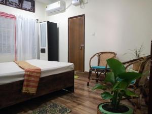 une chambre avec un lit, une chaise et une plante dans l'établissement Globetrotters homestay, à Jorha