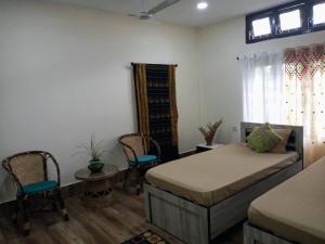 a bedroom with two beds and chairs and a window at Globetrotters homestay in Jorhāt