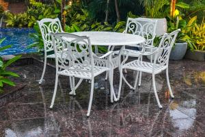 una mesa blanca y cuatro sillas bajo la lluvia en Mayfair Oasis Resort & Convention, en Jhārsuguda