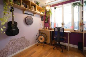 Zimmer mit einem Schreibtisch und einer Gitarre an der Wand in der Unterkunft L'Exotique - T2 Proche Paris & Bois de Vincennes in Saint-Mandé