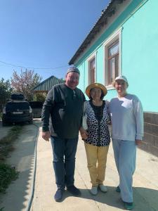 Ein Mann und zwei Frauen stehen vor einem Haus in der Unterkunft Guest house В гостях у Лаззат in Türkistan