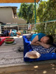 a young boy sleeping on a blue blanket on a bench at Guest house В гостях у Лаззат in Türkistan