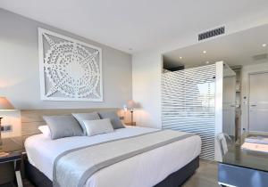 a white bedroom with a large bed and a window at Le Spinaker in Le Grau-du-Roi