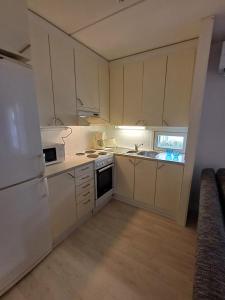 a kitchen with white cabinets and a white refrigerator at Pikiruukin kruunu in Kokkola