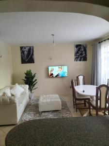 een woonkamer met een witte bank en een tafel bij Johari Shared Studio Westlands in Nairobi