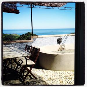 a patio with a table and a tub with a view of the ocean at B&B La Terrazza Di Case Bastei in Ventimiglia