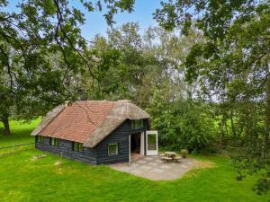 a small house with a thatched roof in a field at Prachtig vrijstaand familiehuis op groot perceel in Scherpenzeel