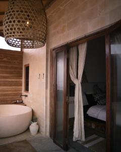 a bathroom with a tub and a bedroom with a bed at La Beach Penida in Nusa Penida