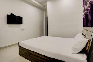 um pequeno quarto branco com uma cama e uma televisão em OYO New Knaha In em Aurangabad