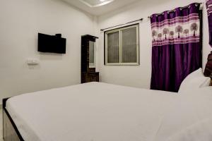 um quarto com uma cama branca e cortinas roxas em OYO New Knaha In em Aurangabad