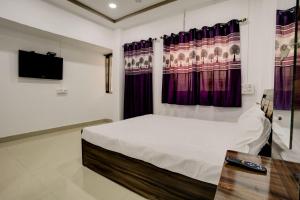 um quarto com uma cama, uma televisão e cortinas em OYO New Knaha In em Aurangabad