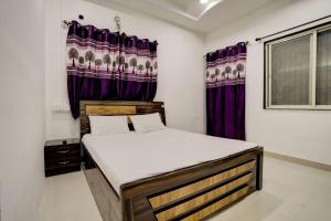 um quarto com uma cama com cortinas roxas em OYO New Knaha In em Aurangabad