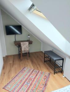 a attic room with a desk and a table and a rug at Rosenappartement-Deutschkreutz in Deutschkreutz