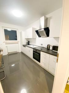 uma cozinha com armários brancos e um forno com placa de fogão em 1-3 Pers. 0,9 km zum Zentrum - moderne Wohnung in Remscheid em Remscheid