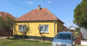 ein Auto, das vor einem gelben Haus parkt in der Unterkunft Веселый домик in Lazarevo