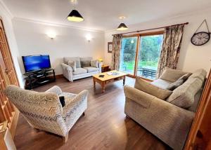 a living room with two couches and a tv at Stob Binnein Cottage in Crianlarich