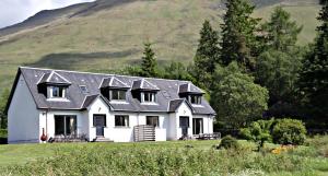 a white house with a mountain in the background at Stob Binnein Cottage in Crianlarich