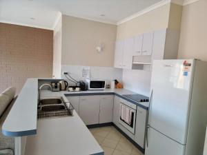 a kitchen with white cabinets and a white refrigerator at Tuggeranong Short Stay #09C - Sleeps 4 in Canberra