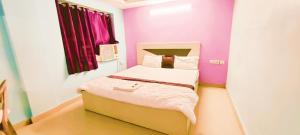 a small bed in a room with purple walls at Goroomgo Chandrabindu Near Sea Beach Puri in Puri