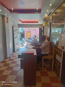 a man sitting at a counter in a store at Goroomgo Chandrabindu Near Sea Beach Puri in Puri