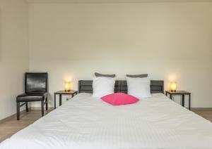 a white bed with a pink pillow and two chairs at L'Antre d'Eux - Suite avec sauna et jacuzzi 