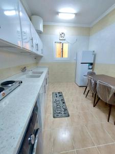 a kitchen with a table and a white refrigerator at شقة واسعة غرفتين نوم وصالة in Tabuk
