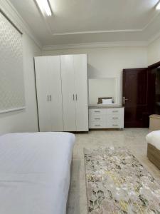 a bedroom with a bed and white cabinets and a rug at شقة واسعة غرفتين نوم وصالة in Tabuk
