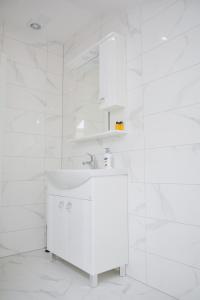 ein weißes Badezimmer mit einem Waschbecken und einem Spiegel in der Unterkunft Hotel Divanhana in Brčko