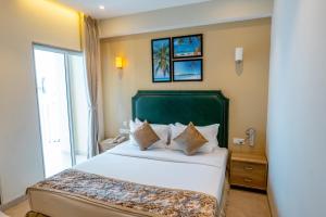 a bedroom with a large bed with a green headboard at Hotel Flora Inn Male Maldives in Male City