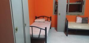 Habitación con 2 camas y pared de color naranja. en Executive Sharing Bed With Other Male Guests, en Sharjah