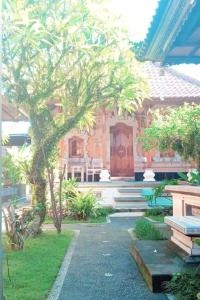 a house with a tree and a wooden door at Umah Arya Homestay in Gianyar