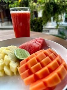 un piatto di cibo con frutta e una bevanda su un tavolo di Umah Arya Homestay & Spa a Gianyar