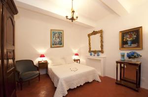 ein Schlafzimmer mit einem Bett, einem Stuhl und einem Spiegel in der Unterkunft La Maison du Peintre en Provence in Mallemort