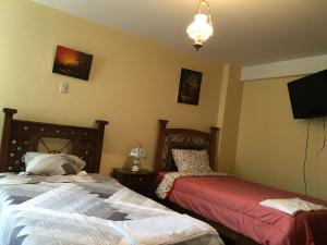 a bedroom with two beds and a flat screen tv at El Seminario Hospedaje in Cajamarca