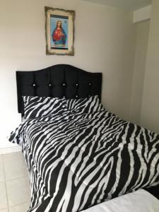 uma cama com lençóis brancos e pretos com estampas de zebra em El Seminario Hospedaje em Cajamarca