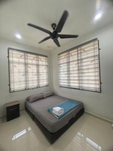 a bedroom with a ceiling fan and two windows at Homestay Cendana Gong Badak in Kampong Tanjong Gelam