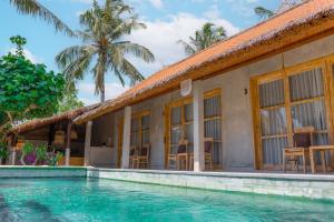 a villa with a swimming pool in front of a house at Golden Garuda Cottages in Polilit